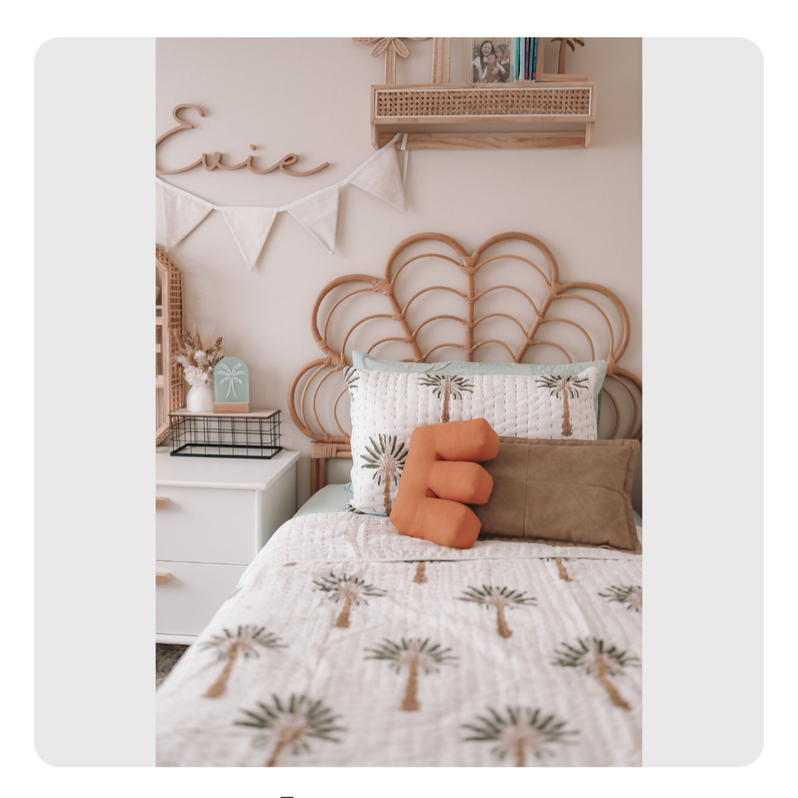 Bedroom scene with a white bed, rattan headboard, and palm tree patterned quilt on a smartphone screen.